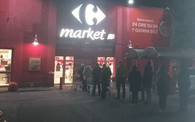 Largas filas frente a los supermercados, de noche, antes de la cuarentena