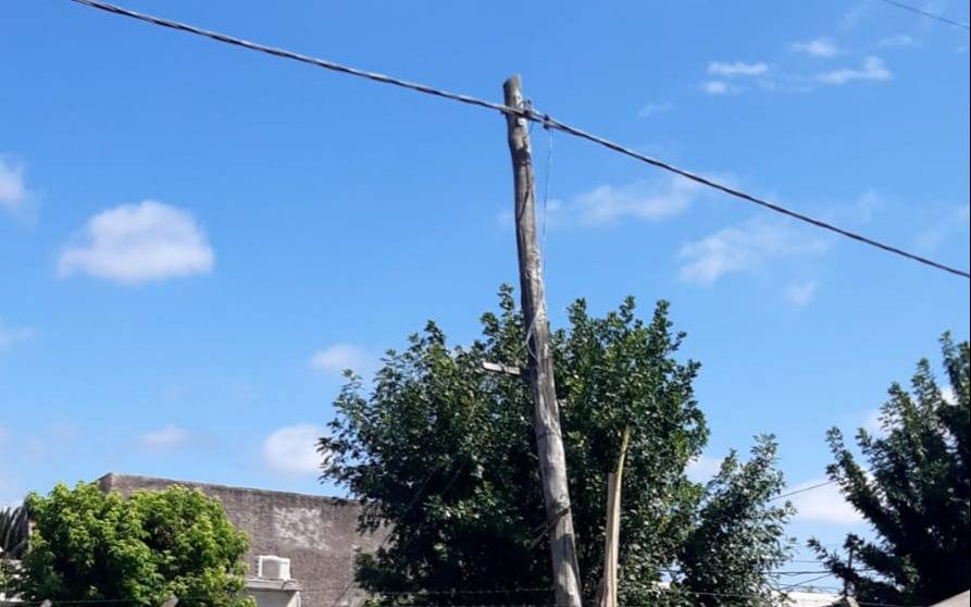 Un poste de luz quebrado lleva tres meses sostenido solo por el tendido eléctrico en 33 y 145 bis