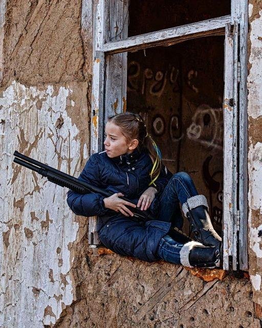 La nena con un rifle en la mano y un chupetín en la boca