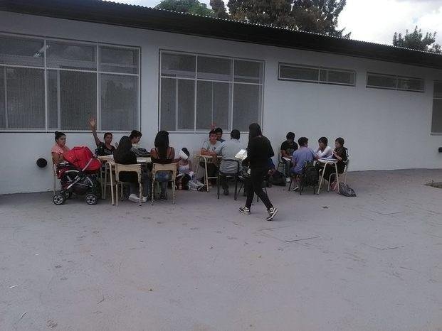 Una escuela con edificio nuevo y clases en el patio