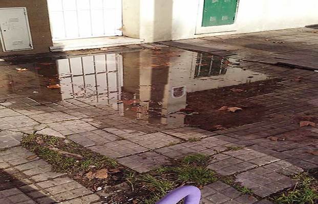 Una mujer embarazada advierte por un 
charco de agua en la puerta de su casa