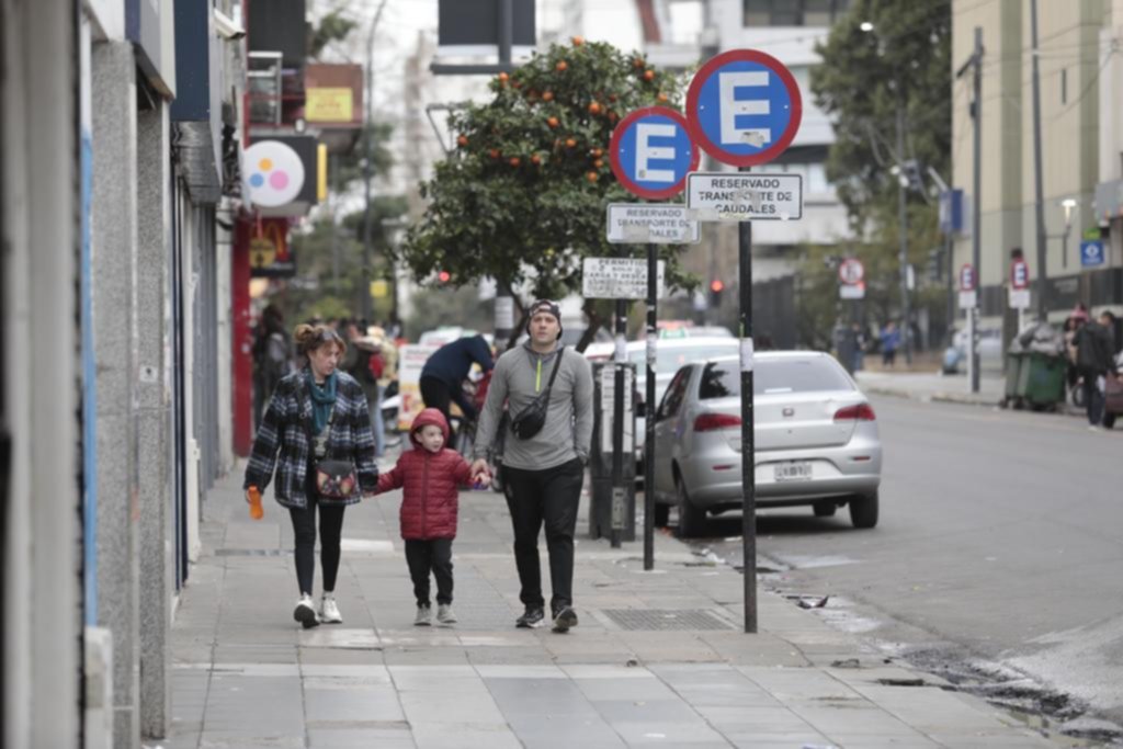 Ciudad casi desierta en la jornada de feriado con cielo gris, frío y llovizna