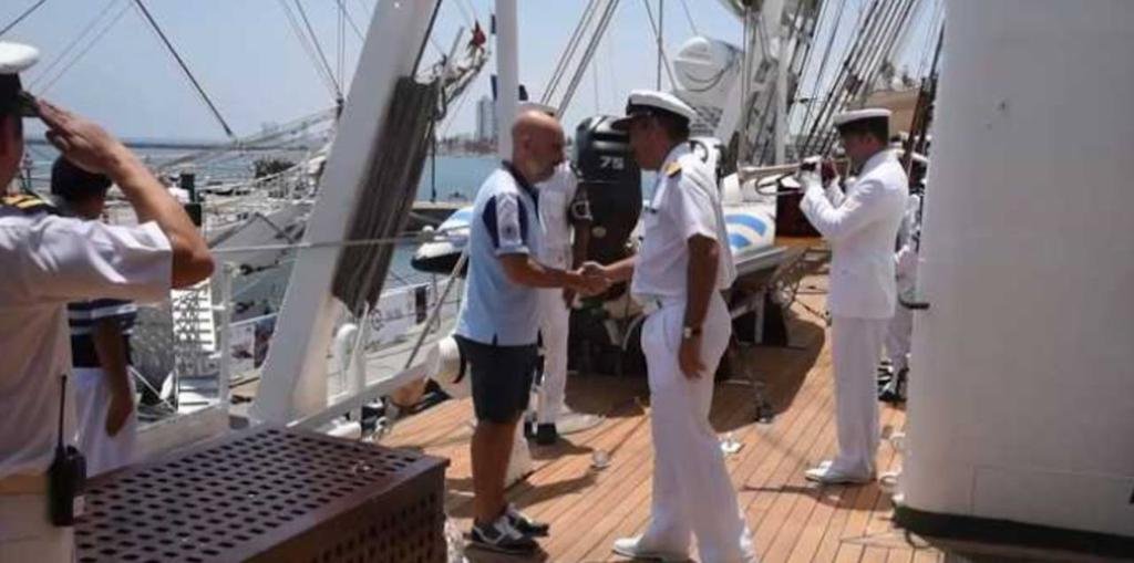 Un embajador en bermudas y zapatillas para recibir a los marinos de la Fragata Libertad