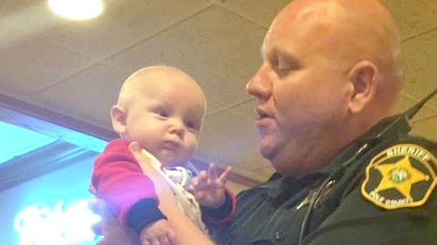 Un oficial distrae a una bebé para que sus padres puedan cenar