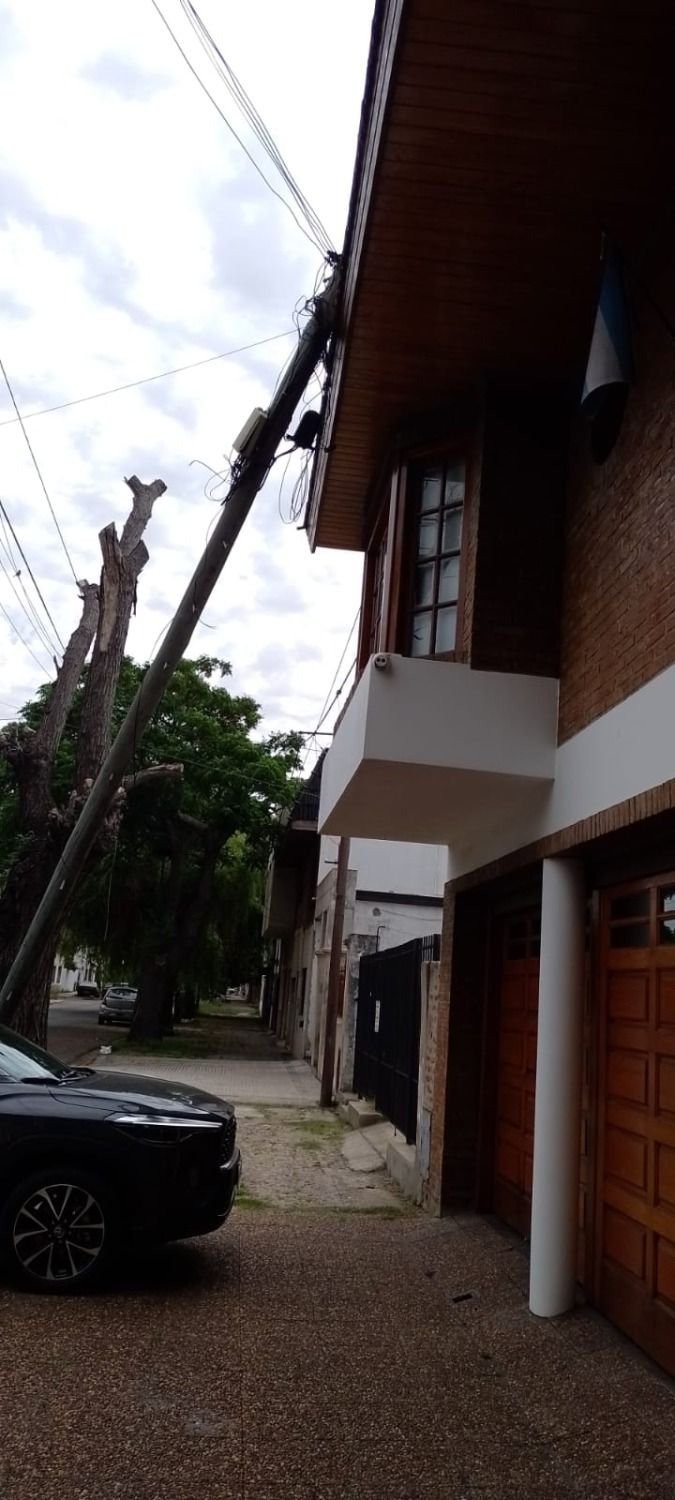 Un viejo poste de tendido telefónico se vino abajo y quedó apoyado en una casa